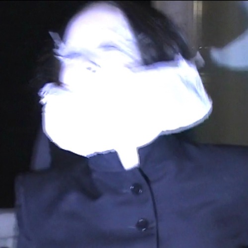 Allie X – Midnight for the Masses single cover: a blurred, flash-lit photo of a dark-haired figure whose face is blown out to white, wearing a navy buttoned jacket against a dark background
