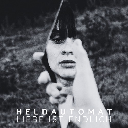 Heldautomat – Liebe ist endlich single cover: black-and-white photo of a woman's face seen in a hand-held mirror shard