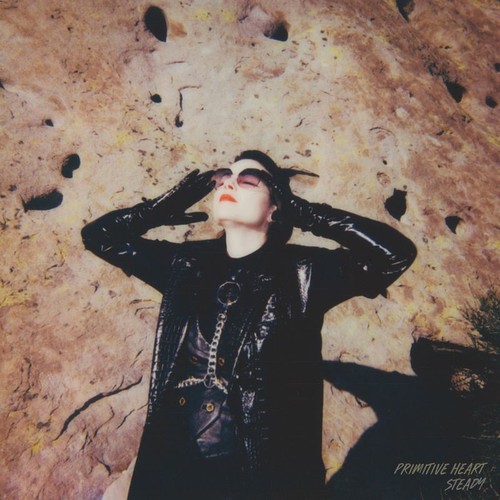 Primitive Heart – Steady single cover: a woman in black patent leather and sunglasses lying back against a sunlit rock face, hands raised to her head
