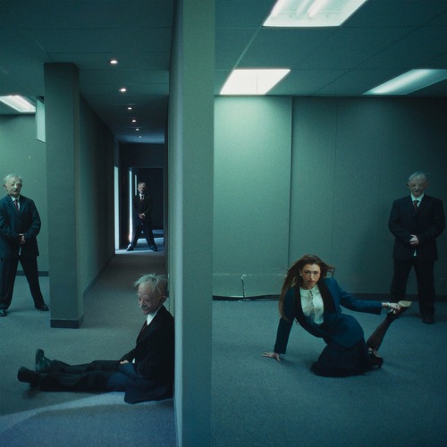 Rêve – Church Of Sound single cover: a woman in a dark blazer and skirt poses on the carpet of a teal-lit office corridor while older men in dark suits stand watching and another sits slumped against a pillar