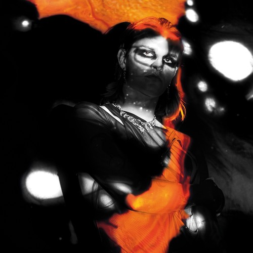 St. Digue – Secret Language album cover: a black-and-white portrait of a figure with dark eye make-up and a jewelled necklace, washed in bright orange, against a black background dotted with white blurred lights